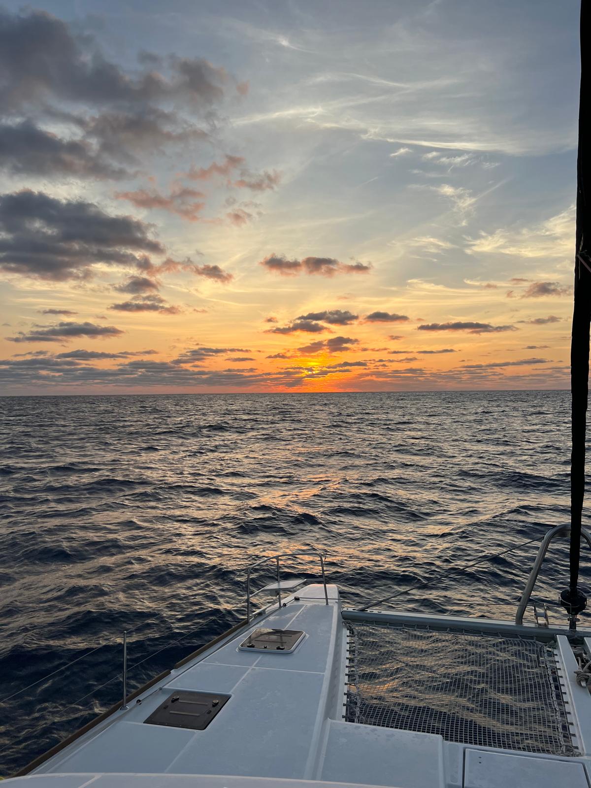 Open ocean sunset over bow and trampolines