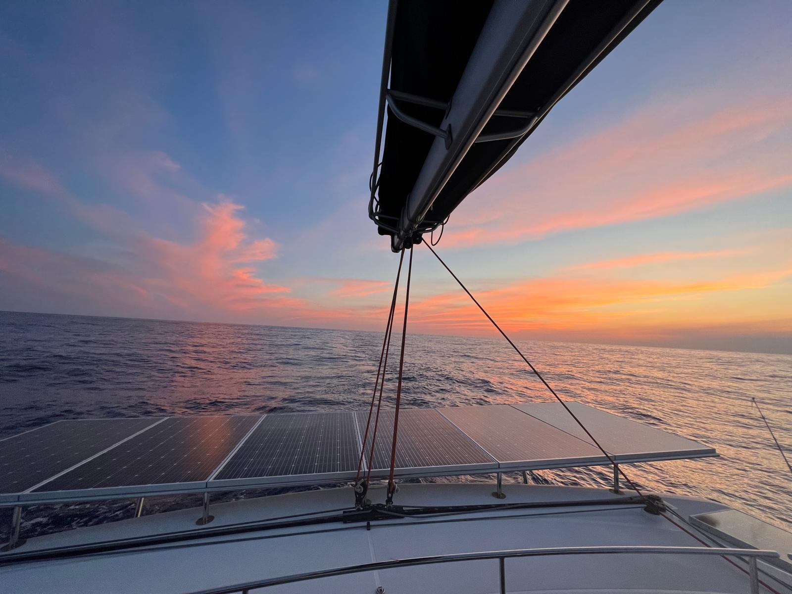 Pink sunset over open water with solar panels